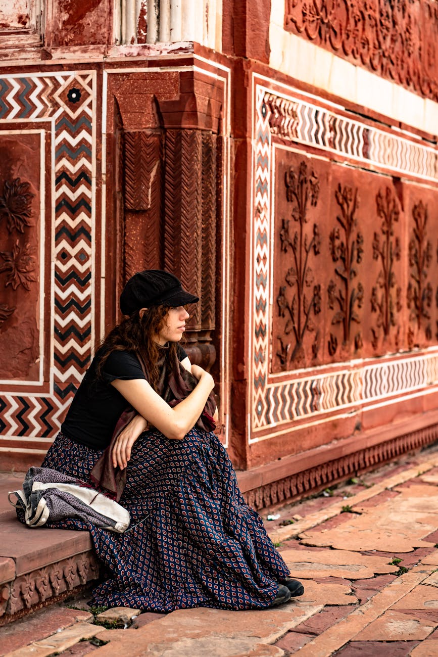 contemplative woman sitting by ornate red wall