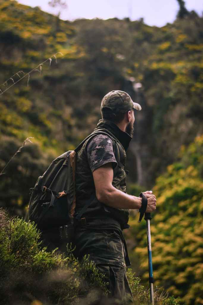 man wearing cap and crew neck shirt standing in the middle of forest