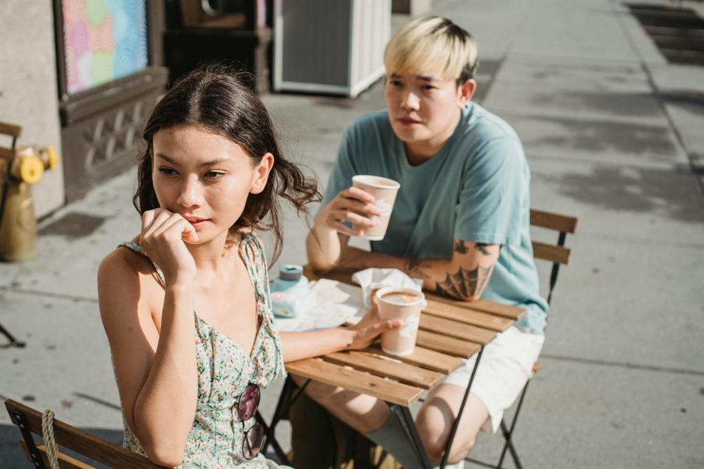 multiracial couple with takeaway coffee at table on street