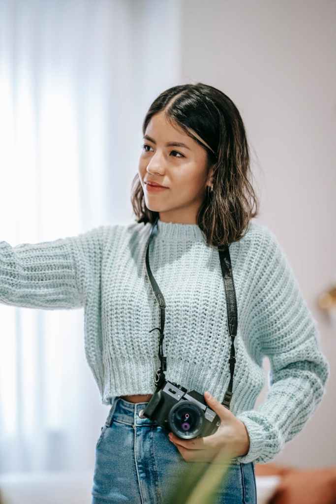 smiling ethnic photographer with photo camera at home