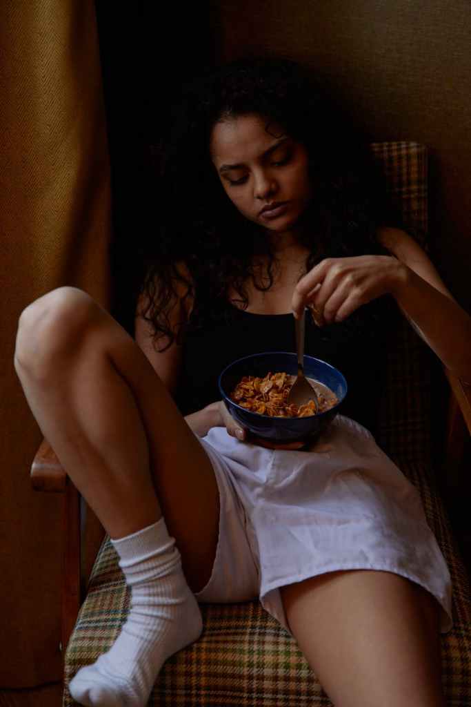 a woman eating alone while sitting on a chair