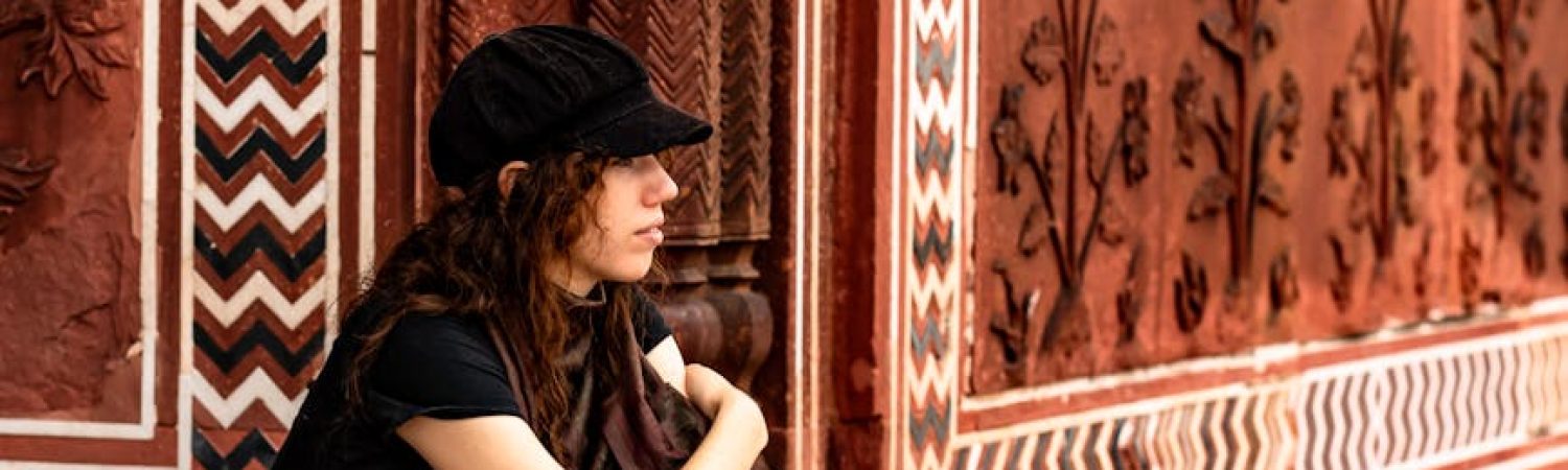 contemplative woman sitting by ornate red wall