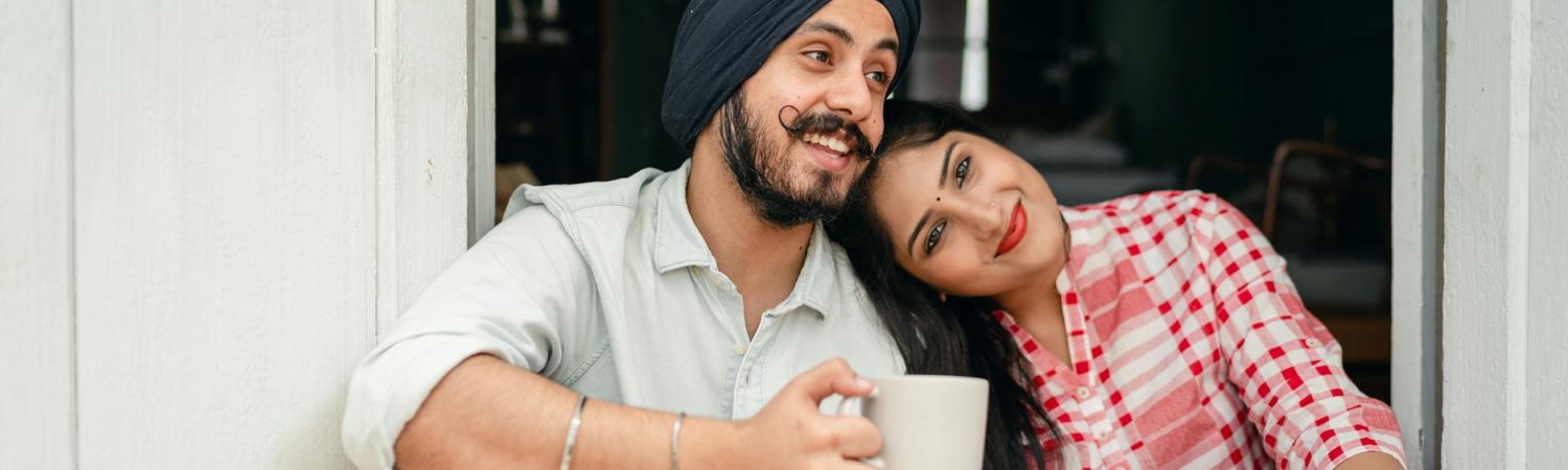 positive married couple relaxing on threshold of house